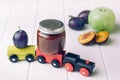 Jar with baby food plum puree and fresh plum on the toy wooden t Royalty Free Stock Photo