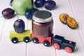 Jar with baby food plum puree and fresh plum on the toy wooden t Royalty Free Stock Photo