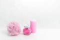 A Jar of bath salt, a sponge for bath and a candle are stand nearby. Light pink objects on a white background. The