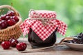 Jar of cherries jam, basket of cherries, saucer and spoon on table Royalty Free Stock Photo