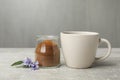 Jar with chicory powder, cup and flowers on light grey table