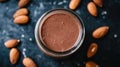 A jar of chocolate smoothie surrounded by almonds on a dark surface Royalty Free Stock Photo