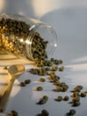 A jar of coffee beans spilled out with wooden spoon on white background, studio shoot indoors day time. Royalty Free Stock Photo