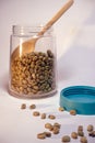 A jar of coffee beans with wooden spoon on white background, studio shoot indoors day time. Royalty Free Stock Photo