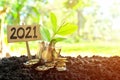 Jar of coins on soil with growing plant beside a 2021 sign. Start wise by investing or grow money in business on year 2021 concept Royalty Free Stock Photo