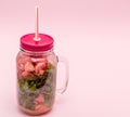 Jar of cold fresh lemonade with piece of watermelon and drinking straws on pink background