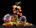 Jar of colorful farfalle pasta on wooden table isolated on black background