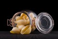 Jar of conchiglie pasta shell on wooden table isolated on black background Royalty Free Stock Photo