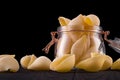 Jar of conchiglie pasta shell on wooden table isolated on black background Royalty Free Stock Photo