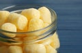 Jar of delicious crispy corn sticks on blue wooden table, closeup