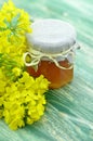 Jar of delicious honey in a jar with rapeseed flowers