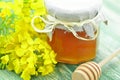 Jar of delicious honey in a jar with rapeseed flowers