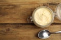 Jar of delicious mayonnaise and spoon on wooden table, flat lay. Space for text Royalty Free Stock Photo