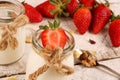 Jar with delicious yogurt and strawberry and granola muesli, over a white on wooden table Royalty Free Stock Photo