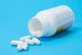 A jar of dietary supplements and white capsules on a blue background. Vitamins and trace elements for a complete diet Royalty Free Stock Photo
