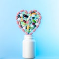 Jar of different tablets and pills in shape of heart on top of it. Multi-colored pills in the shape of heart on. Concept Royalty Free Stock Photo