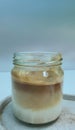 A jar of Dirty Coffee on white wooden tray and background, espresso shot over cold milk created gradient layer, decorated with a Royalty Free Stock Photo