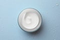 Jar of face cream on light blue surface covered with water drops, top view Royalty Free Stock Photo