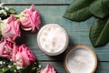 Jar of face cream and pink roses on light blue wooden table, flat lay Royalty Free Stock Photo