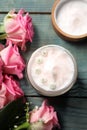 Jar of face cream and pink roses on light blue wooden table, flat lay Royalty Free Stock Photo