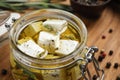 Jar with feta cheese marinated in oil on wooden table. Pickled food Royalty Free Stock Photo
