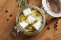 Jar with feta cheese marinated in oil on wooden table. Pickled food Royalty Free Stock Photo