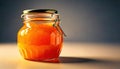 Bright orange honey jar sits on a smooth surface illuminated by soft light