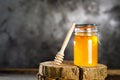 Jar with fresh bee honey and wooden dipper on a gray background. Space for text Royalty Free Stock Photo