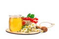 A jar of fresh honey, chamomile and red currants on a white background.