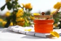 Jar with fresh rose honey on white wooden table. Space for text