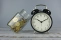 Jar of gold coins and clock. money and time concept