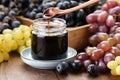 Jar of grape molasses, grape syrup. Sweetener, cough medicine. Black, green and purple grapes on table