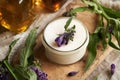 A jar of homemade comfrey ointment with fresh blooming symphytum officinale plant