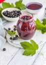 Jar of homemade fresh currant jam with shugar. Fresh berries black currant on white wooden background