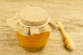 Jar of honey closed jute cloth drizzler on wooden background