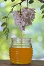 Jar of honey with flowers of acacia on table