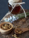 Jar of honey, flowers and wooden bowl of propolis granules on piece of wood. Royalty Free Stock Photo