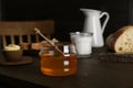 Jar with honey, milk, bread and butter on wooden table Royalty Free Stock Photo