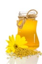 The jar of honey near a pile of pollen and flower