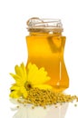 The jar of honey near a pile of pollen and flower
