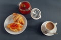 A jar of jam, a fresh croissant smeared with jam, and a cup of coffee with cream for breakfast. Royalty Free Stock Photo