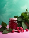 Jar of jam with raspberries and mint leaves on delicate color background.