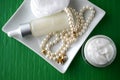 A jar of luxury beauty face cream and serum bottle with pearls on emerald green color background with copy space. Royalty Free Stock Photo