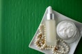 A jar of luxury beauty face cream and serum bottle with pearls on emerald green color background with copy space. Royalty Free Stock Photo