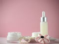 A jar of luxury beauty face cream and serum bottle with pearls on pink color background with copy space. Royalty Free Stock Photo