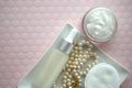 A jar of luxury beauty face cream and serum bottle with pearls on pink color background with copy space. Royalty Free Stock Photo