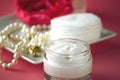 A jar of luxury beauty face cream and serum bottle with pearls on pink color background with copy space. Royalty Free Stock Photo