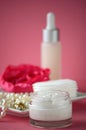 A jar of luxury beauty face cream and serum bottle with pearls on pink color background with copy space. Royalty Free Stock Photo