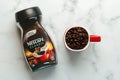 Jar of Nescafe Classic and red cup of Nescafe with coffee beans