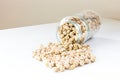 Jar of non-perishable cooked chick peas with dried chick peas spilled on the table